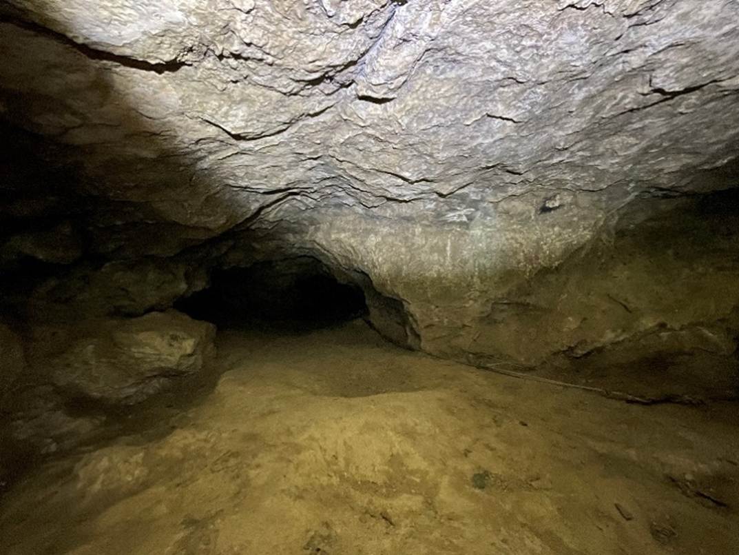 A cave with a light shining on the ceiling
Description automatically generated